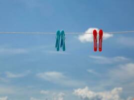 rouge et bleu pinces à linge sur une corde contre le Contexte de une brillant bleu ciel avec des nuages. haute qualité photo