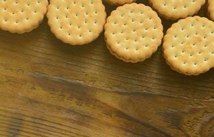 un biscuit sandwich rond fourré à la noix de coco se trouve en grande quantité sur une surface en bois marron. photo de friandises comestibles sur un fond en bois avec espace de copie