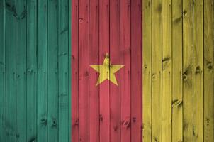 Cameroun drapeau représenté dans brillant peindre couleurs sur vieux en bois mur. texturé bannière sur rugueux Contexte photo