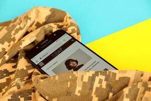 Kyiv, Ukraine - 4 peut, 2023 aujourd'hui ua ukrainien nouvelles portail sur téléphone intelligent écran avec ukrainien drapeau et camouflage en tissu photo