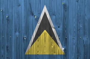 Saint lucia drapeau représenté dans brillant peindre couleurs sur vieux en bois mur. texturé bannière sur rugueux Contexte photo