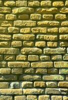 texture de mur vertical de plusieurs rangées de maçonnerie très ancienne en brique rouge. mur de briques brisé et endommagé avec des coins pincés photo