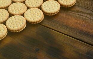 un biscuit sandwich rond fourré à la noix de coco se trouve en grande quantité sur une surface en bois marron. photo de friandises comestibles sur un fond en bois avec espace de copie