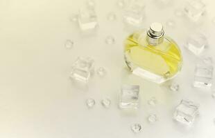 bouteille jaune de parfum féminin, photographie objective de la bouteille de parfum dans des glaçons et de l'eau sur un tableau blanc. vue d'en-haut. photo de produit maquette, concept de fraîcheur