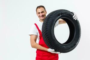 portrait de souriant Masculin mécanicien en portant pneu sur blanc Contexte photo