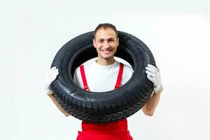 mécanicien porter une pneu sur une blanc Contexte photo