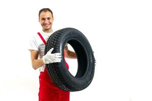 mécanicien porter une pneu sur une blanc Contexte photo