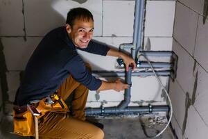 Jeune Masculin plombier fait du câblage de égout tuyaux photo
