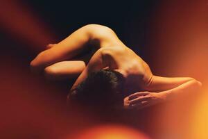 méconnaissable femelle avec nu corps mensonge dans noir studio photo