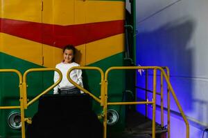 une peu fille des stands suivant à une grand locomotive. photo