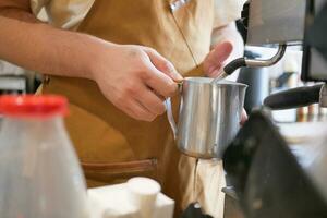 le café machine est faire mousser lait. barista mains tenir une cruche de lait. photo