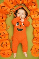 Halloween portrait de adorable bébé mensonge sur vert Contexte suivant à citrouille guirlande photo