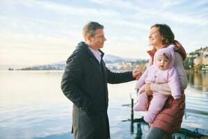 Extérieur portrait de content Jeune couple avec adorable bébé fille profiter agréable vue de hiver Lac Genève ou lac Léman, Montreux, Suisse photo