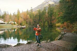 Extérieur portrait de content milieu âge femme prise des photos par le lac, Voyage et actif mode de vie concept