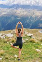 Extérieur portrait de content Jeune femme pratiquant yoga dans montagnes pendant randonnée, actif mode de vie photo