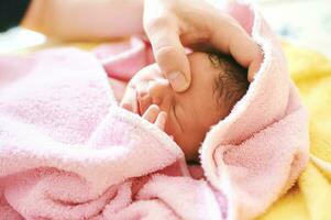 nouveau née bébé couvert dans serviette après prise bain, père en essayant à calme vers le bas bébé avec tête massage photo