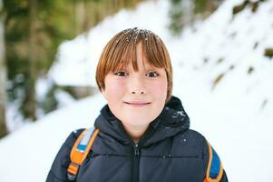 Extérieur portrait de mignon enfant randonnée dans hiver forêt, Jeune garçon portant retour retour randonnée dans montagnes photo