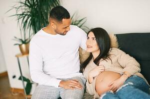 intérieur portrait de content Jeune couple, Enceinte femme repos sur une canapé avec sa aimant mari photo