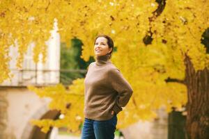 l'automne portrait de magnifique mature femme, relaxant dans d'or tomber parc photo