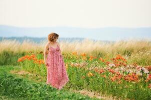 Extérieur portrait de magnifique milieu âge femme profiter agréable journée dans lis jardin, portant rouge robe, content et en bonne santé mode de vie photo