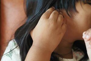 enfant fille ayant des douleurs à l'oreille touchant son oreille douloureuse, photo