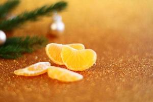 mandarine fraîche orange pelée et arbre de noël en fourrure verte sur fond de paillettes dorées, décoration de carte de nouvel an, pin et agrumes photo