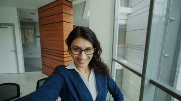 pov de Jeune femme d'affaires dans costume prise une selfie photo en portant téléphone intelligent et avoir amusement dans moderne Bureau à l'intérieur