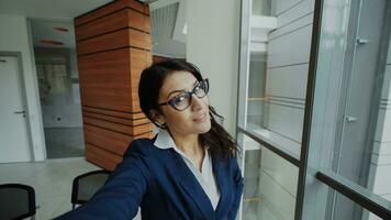 pov de Jeune femme d'affaires dans costume prise une selfie photo en portant téléphone intelligent et avoir amusement dans moderne Bureau à l'intérieur