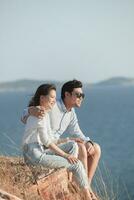 Jeune des couples relaxant sur haute Montagne contre bleu mer Contexte photo