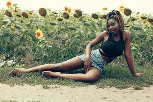 africain américain fille dans une champ de Jaune fleurs à le coucher du soleil photo