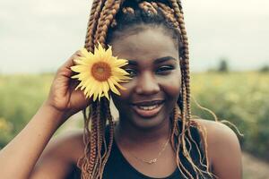 africain américain fille dans une champ de Jaune fleurs à le coucher du soleil photo