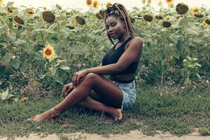 africain américain fille dans une champ de Jaune fleurs à le coucher du soleil photo