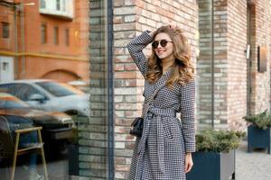 attrayant fille dans une manteau dans le rue dans une ville, Soleil est brillant photo