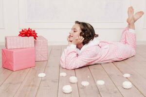 mignonne peu fille dans pyjama avec bonbons séance sur le sol photo