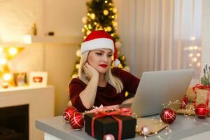 femme en utilisant portable près Noël arbre, en ligne Noël photo