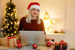 femme en utilisant portable près Noël arbre, en ligne Noël photo