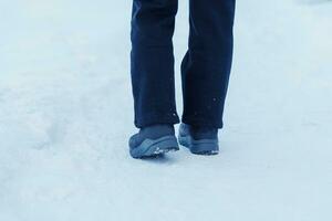 voyageur en marchant sur le neige, fermer imperméable bottes ou des chaussures pendant randonnée sur neigeux forêt. hiver saison photo