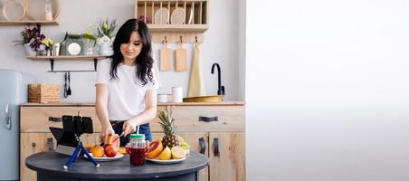 belle brune prépare un smoothie aux fruits à la maison dans la cuisine et supprime le processus de cuisson pour sa chaîne photo