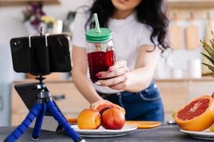 heureuse jeune femme préparant un délicieux smoothie nutritif photo