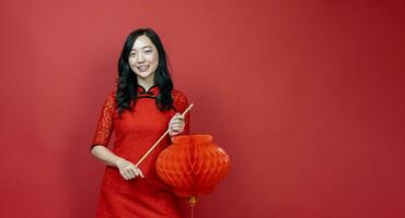 asiatique chinois femme avec rouge cheongsam ou qipao en portant denglong le papier lanterne à souhait le bien la chance et la prospérité dans chinois Nouveau année fête vacances isolé sur rouge Contexte photo