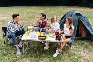 gars assis à table pendant le déjeuner dans le camping et parlant photo