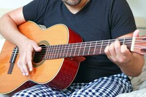 fermer de une homme en jouant guitare à Accueil dans le sien Accueil costume. photo