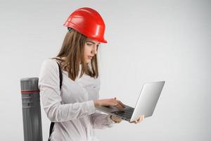 femme architecte se tient avec un tube derrière son dos tenant un ordinateur portable et regardant vers l'écran photo