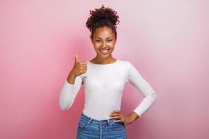 Jeune femme heureuse mulâtre debout avec les pouces vers le haut sur fond rose.- image photo