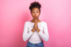 photo de studio d'une femme en posture de supplication sur fond rose regardant la caméra, symbole de demander - image