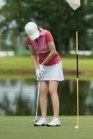 femme golfeur approche pour frappe le golf Balle sur vert photo