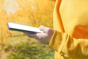 fille dans une Jaune chandail détient une téléphone. le fille les usages le téléphone. photo