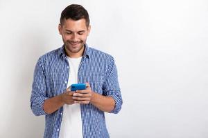 homme séduisant debout tenant un smartphone dans ses mains et regardant l'écran.- image photo