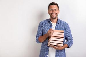 portrait d'un jeune homme heureux nerd tenant des livres dans ses mains. retour à l'école photo