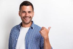 bel homme heureux pointant son gros doigt vers l'arrière et regardant la caméra.- image photo